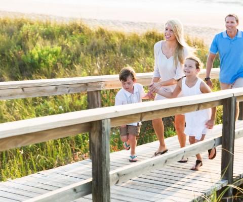 Family crossing bridge toward beach